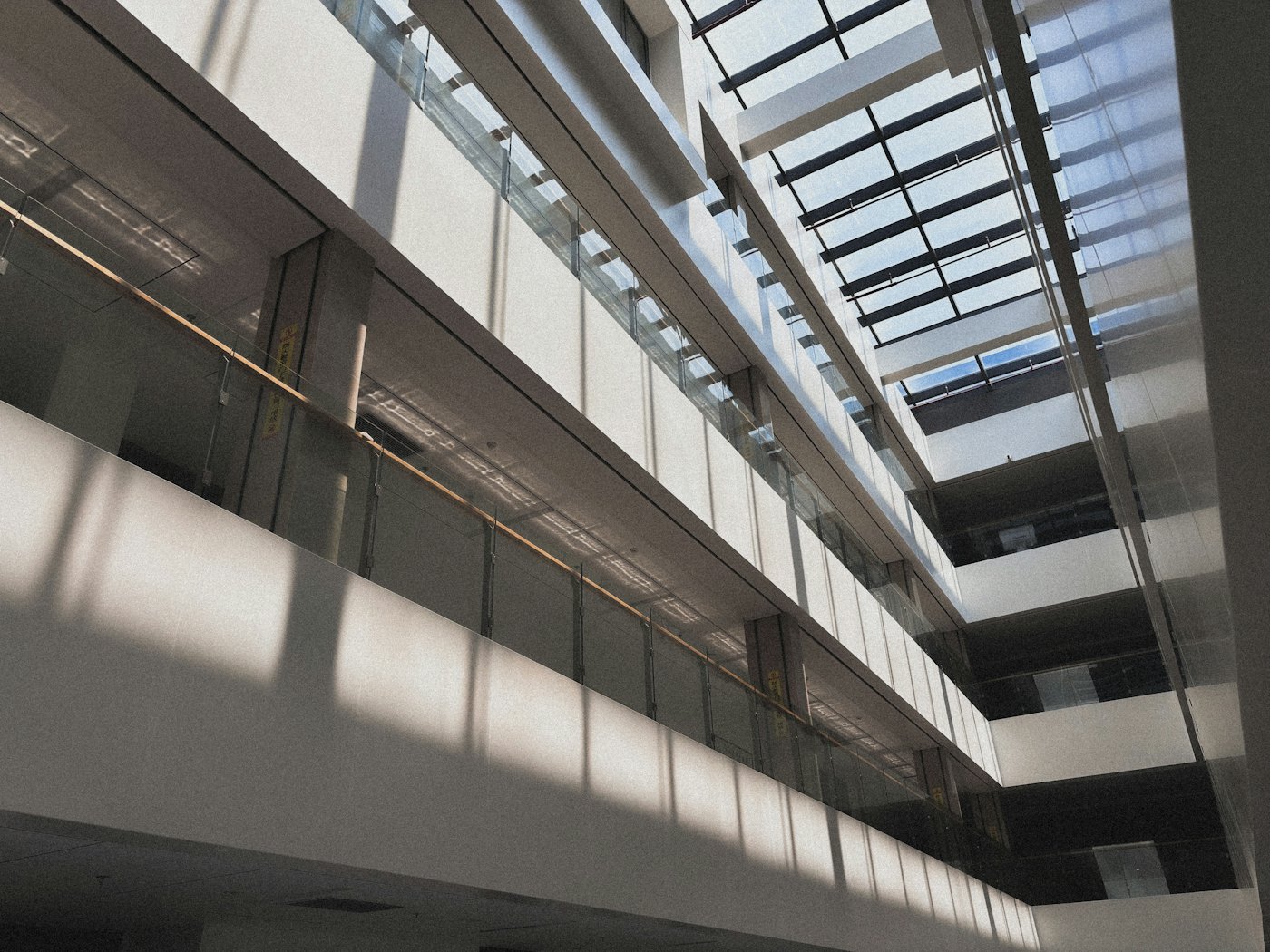 Sunlight through a glass roof falling across the balconies of a tall atrium